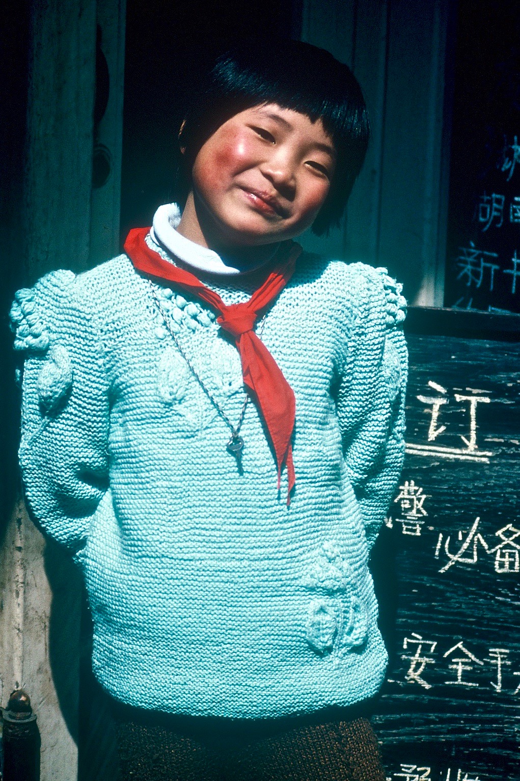 A young Chinese girl in a blue sweater, smiling — scanned film, 1980s